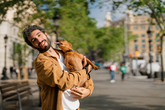 A dog trying to lick the face of his owner during a walk in the city