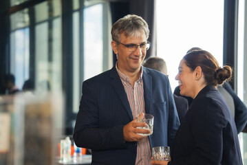 Businessman holding glass talking with business partner at the company gathering or office meeting on New year at the hotel lounge. People building connection and making network