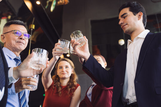 Diverse business team celebrating a milestone or successful deal with a cheerful toast. Happy professionals raising glasses at a corporate social event or New year party. Office team meeting
