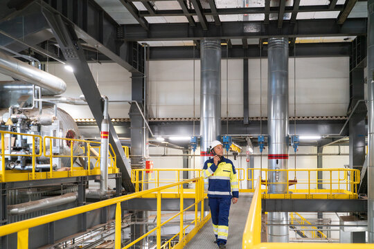 Engineer Using Walkie-talkie While Walking on Walkway in a Power Plant