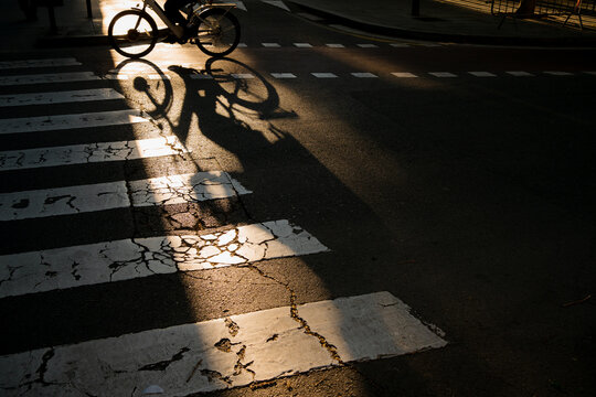 The shadow of a rider on zebra crossing on a street
