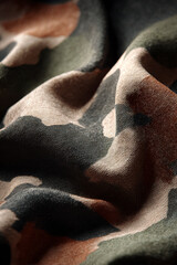 Close-up of camouflage fabric with earth tones, texture and depth.