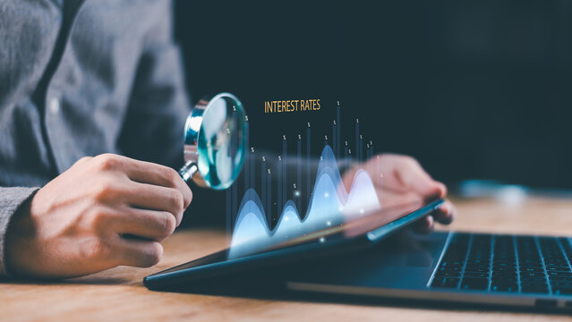 Businessman analyzing financial graph with magnifying glass on digital tablet showing fluctuating interest rates, finance data, investment growth, economic performance analysis for market strategy