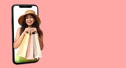 Young African-American woman with shopping bags popping out of smartphone screen on pink background with space for text