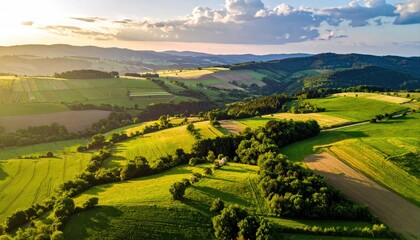 Golden Hour Sunlight Illuminates Rolling Green Hills and Agricultural Fields in a Serene Rural Landscape