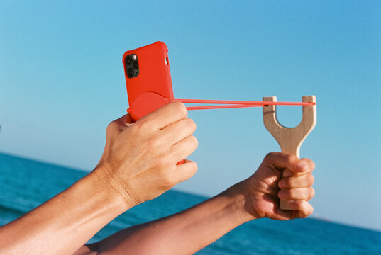 man pulling back a slingshot with a smartphone, 35mm film