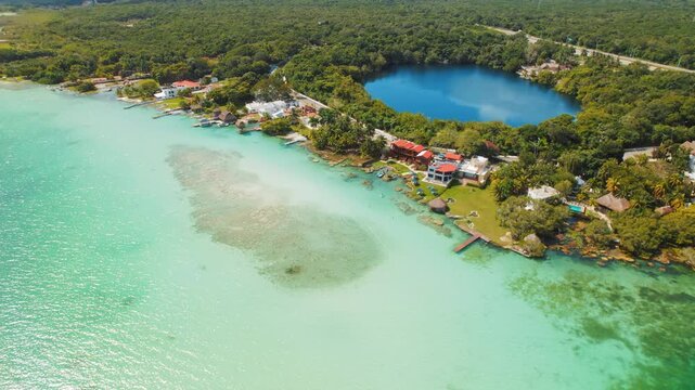 Aerial view of Bacalar lagoon shore with houses and deep blue cenote in Mexico