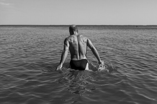 Man Wades Into Tranquil Water on a Sunny Afternoon