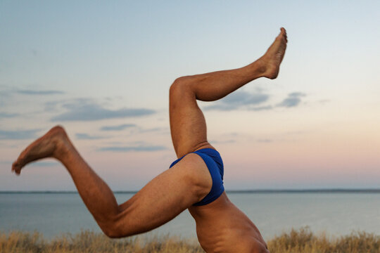 A Man Is Fooling Around Doing A Handstand In Nature