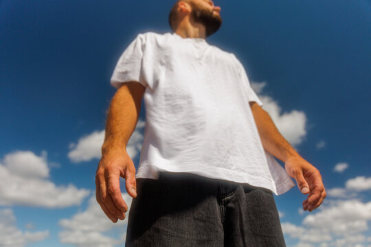 Man Standing Outdoors Under a Blue Sky With Fluffy Clouds