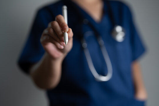Doctor in blue scrubs with stethoscope holding digital stylus, concept of telemedicine, digital healthcare, virtual consultation, and innovation in medical technology for online communication.