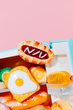 toy fried egg and pastry in a blue crammed fridge 