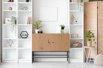 Interior of room with wooden cabinet and shelving units near white wall