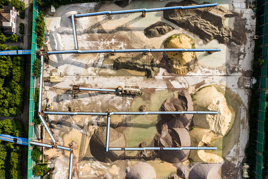 Top view of sand and gravel piles with conveyor belts in storage yard