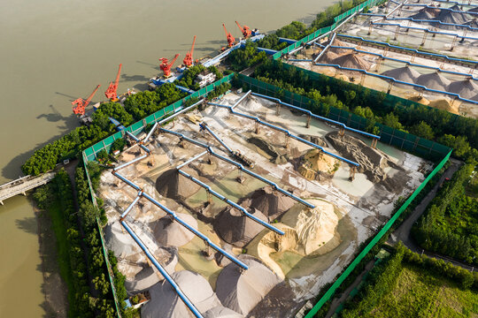 Sand storage yard with conveyor belts and cranes by the river