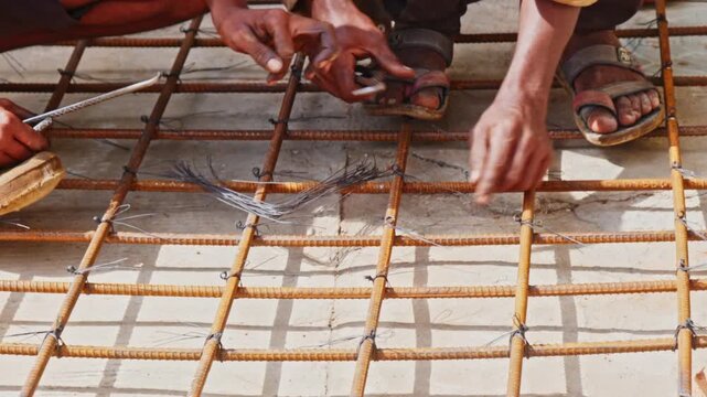 construction workers tying steel reinforcement bars using binding wire at a building site. day time, slight pan shot, 4k.