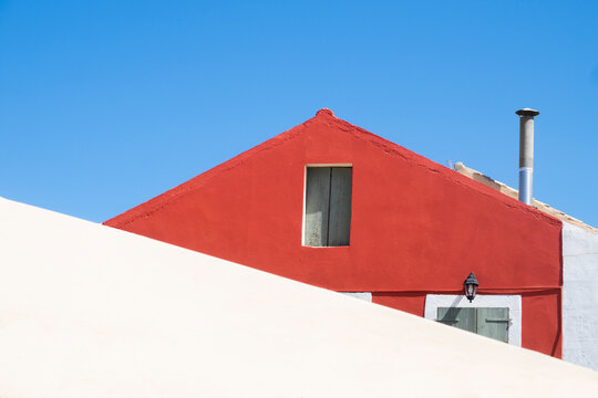 Red house, white wall and blue sky composition