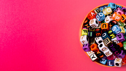Vibrant Alphabet Cube Beads in Orange Dish on Pink Background