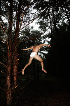 Person Jumps From Tree in Forest During Cloudy Day