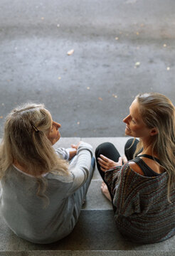 Two women engaging in a heartfelt and serious conversation on the step