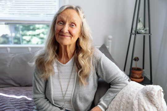 Smiling woman sitting in a bright room with thoughtful expression