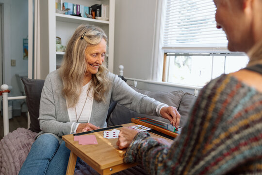Two women enjoying a relaxed game of cards in bright home setting