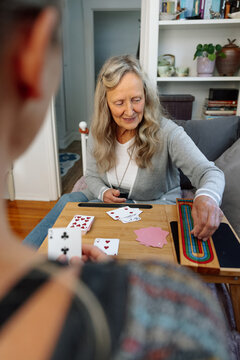 Old woman playing cribbage cards with a friend at a cozy home