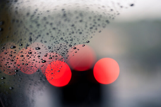 Raindrops on Car Window with Blurred Red Lights
