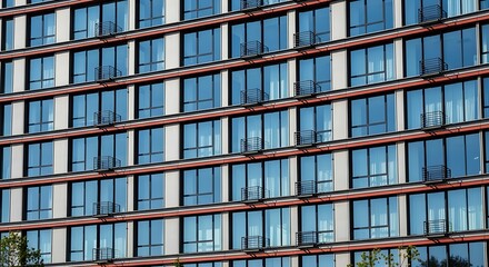 Modern glass facade of a high-rise building with repeating window patterns and reflections.