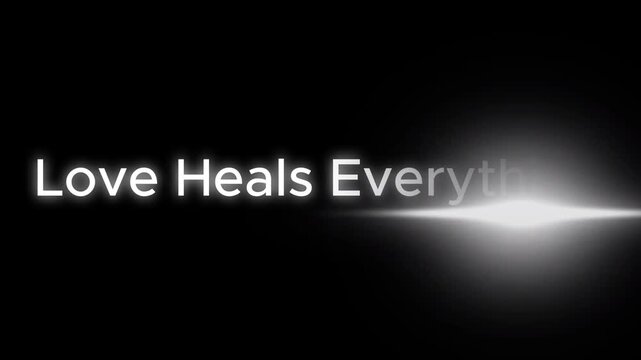 The words love heals everything in white with a bright light on a black background are displayed