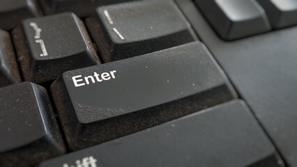 Macro shot on a dusty black computer keyboard, emphasizing the large Enter key, showing technology and connectivity.