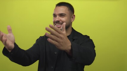 Young hispanic man blows air kiss with both hands toward camera in lime green studio setting; affection.