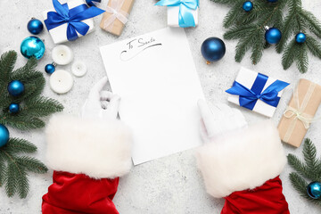 Santa hands with blank letter, Christmas gifts, decorations and candles on light background, closeup