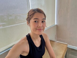 Happy Asian Thai woman smiling and sweating while taking selfie after done work out at gym.