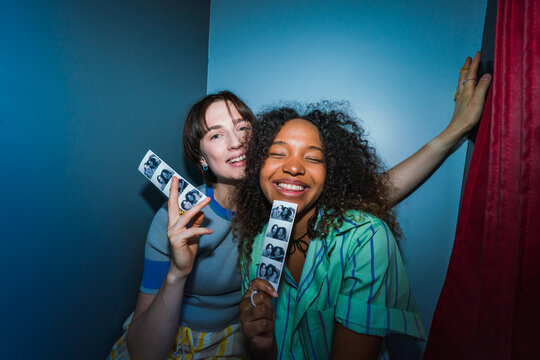 Friends holding photo booth picture strips