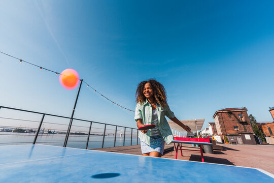 Smiling woman playing ping pong outdoors