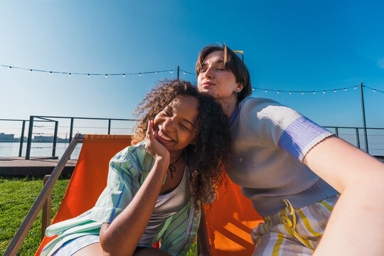 Young women taking selfie in deck chairs outdoors