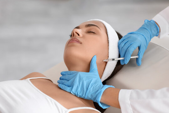 Young woman receiving masseter muscle filler injection in beauty salon
