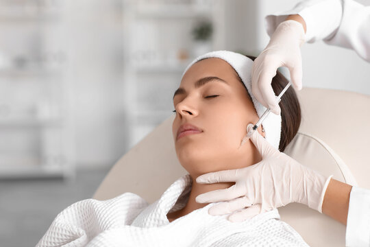 Young woman receiving masseter muscle filler injection in beauty salon