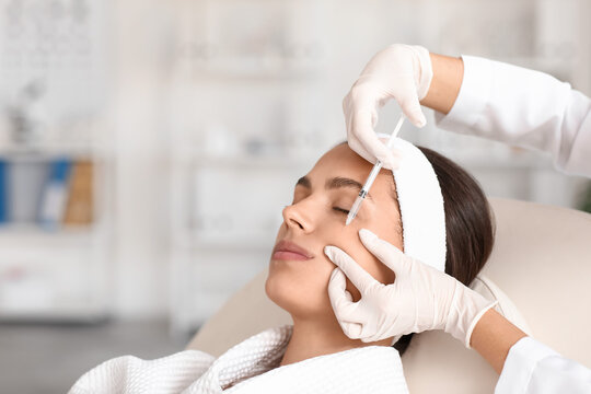 Young woman receiving cheek filler injection in beauty salon