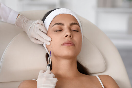 Young woman receiving cheek filler injection in beauty salon