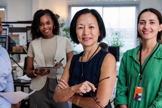Diverse women smiling in a modern office setting.