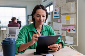 Woman works on tablet in modern office setting.