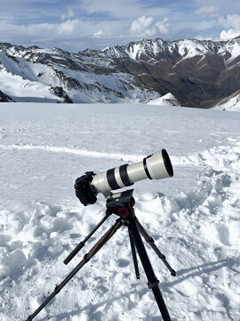 Fototapeta Camera with telephoto lens on snowy slope
