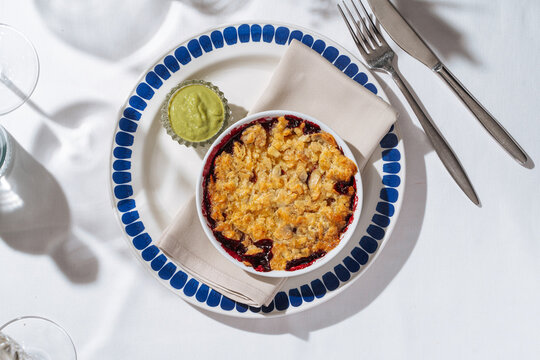 Baked fruit crumble with green sauce on side plate