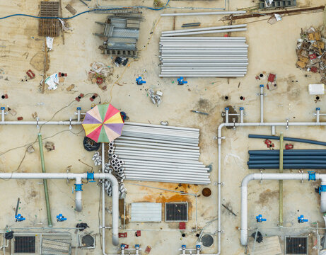 Aerial Construction Site with Stacked Pipes and Colorful Sunshad