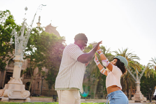 Father and daughter giving high five while roller skating in park