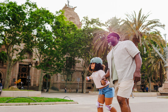 Father teaching daughter roller skating in Barcelona