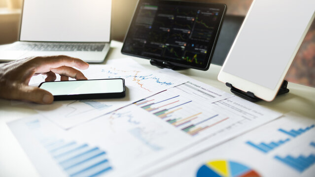 close up shot, Investors using mobile phone working with digital tablet and laptop analyzing investments and use data from charts to plan future investments