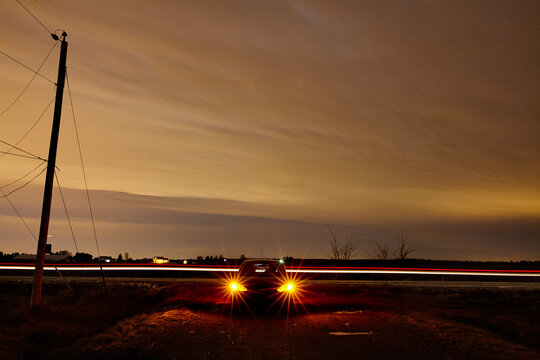 Long exposure of a parked car at night. Taillight trails zoom by